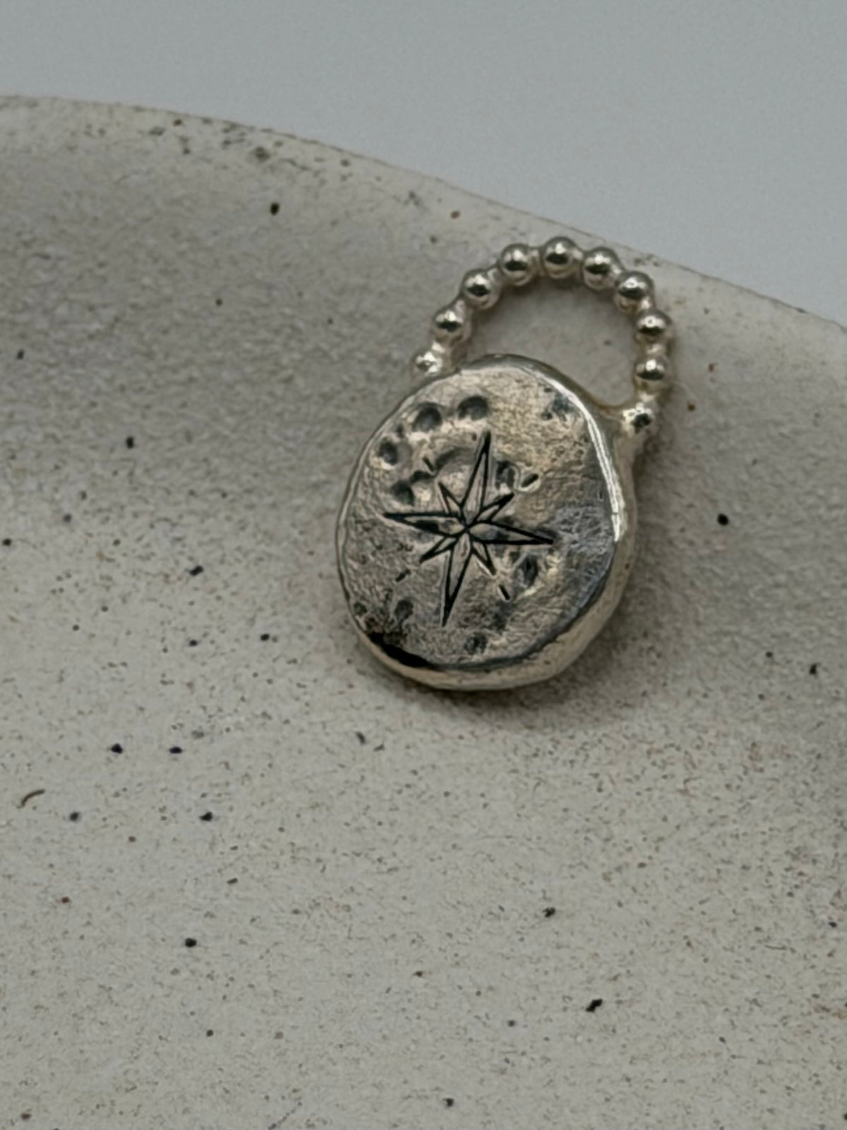 Handmade fine silver Love Lock charm featuring an organic, textured disc with softly rippled detail and a row of beaded silver detail.