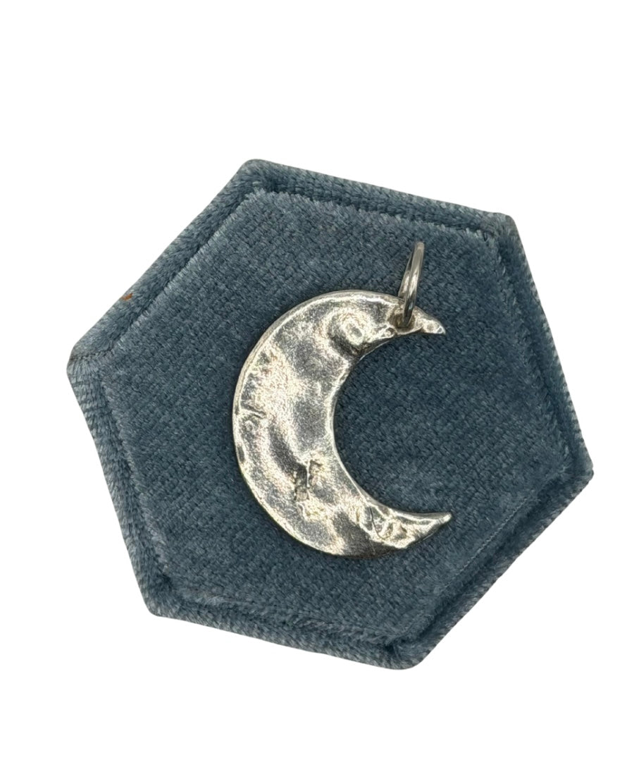 Handmade maxi crescent moon charm crafted from 999 fine silver metal clay, featuring an organic shape and textured finish on a dark green velvet jewellery display.