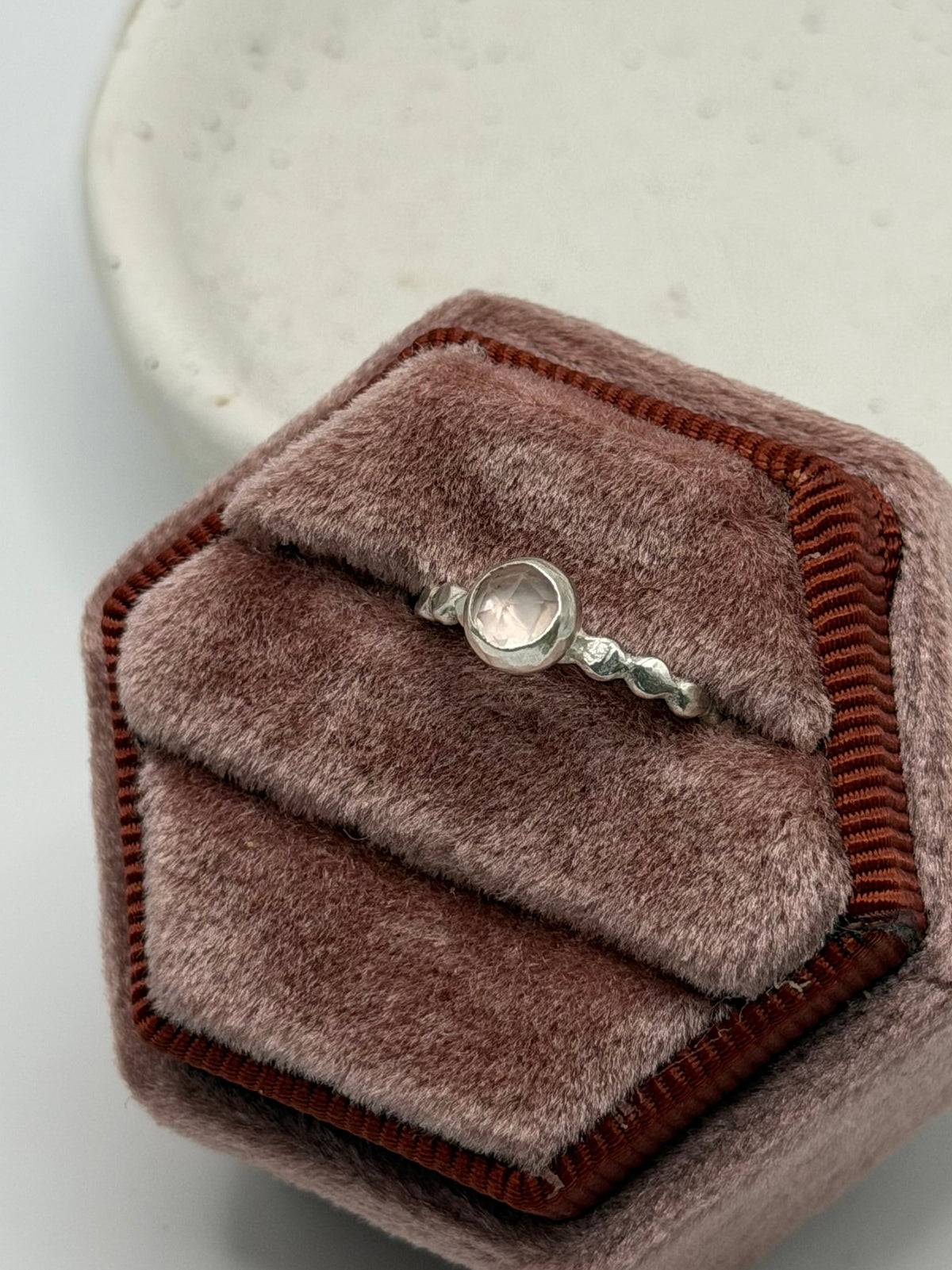 Mini faceted rose quartz ring with a pale pink gemstone set on a textured sterling silver pebble band.