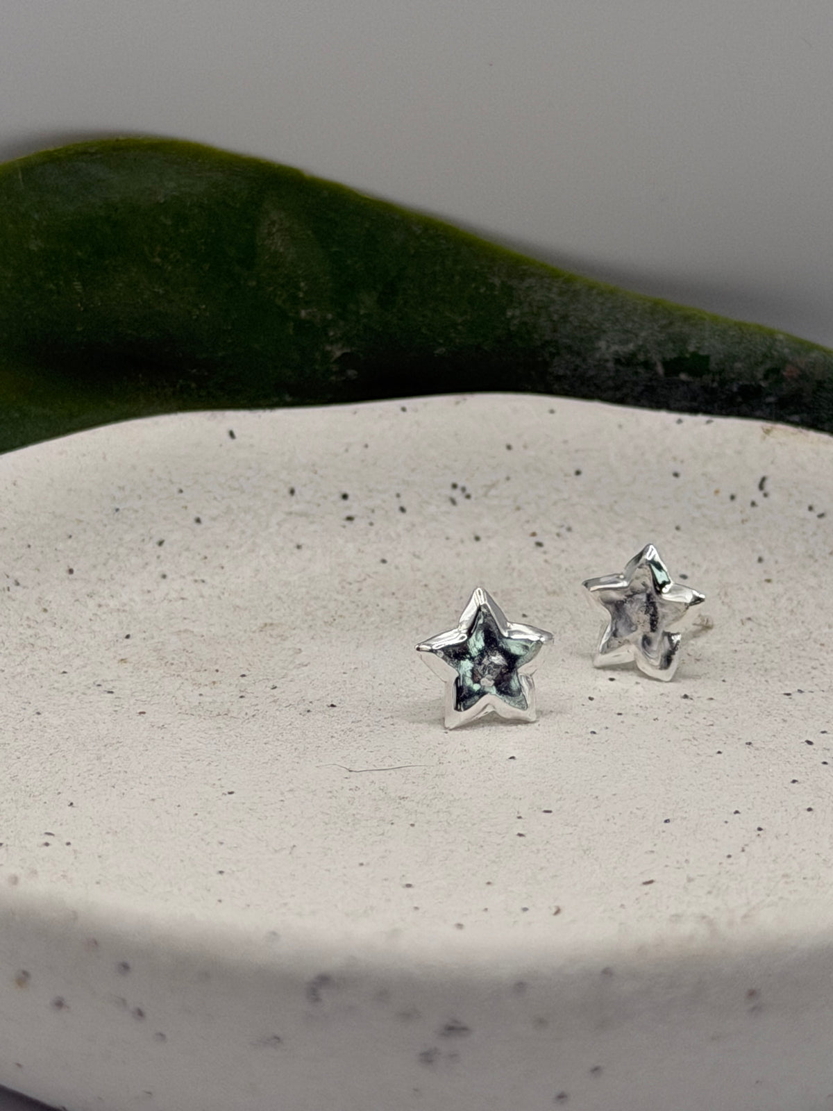 Recycled silver star earrings featuring dimensional points and a softly textured surface.
