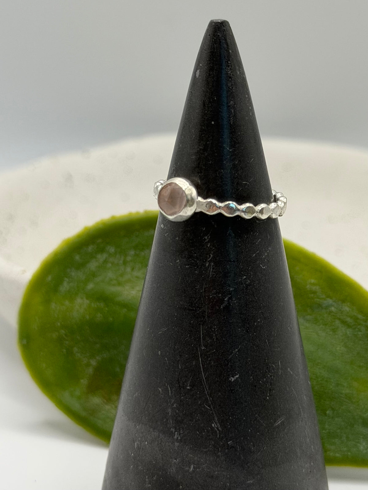 Mini faceted rose quartz ring with a pale pink gemstone set on a textured sterling silver pebble band.