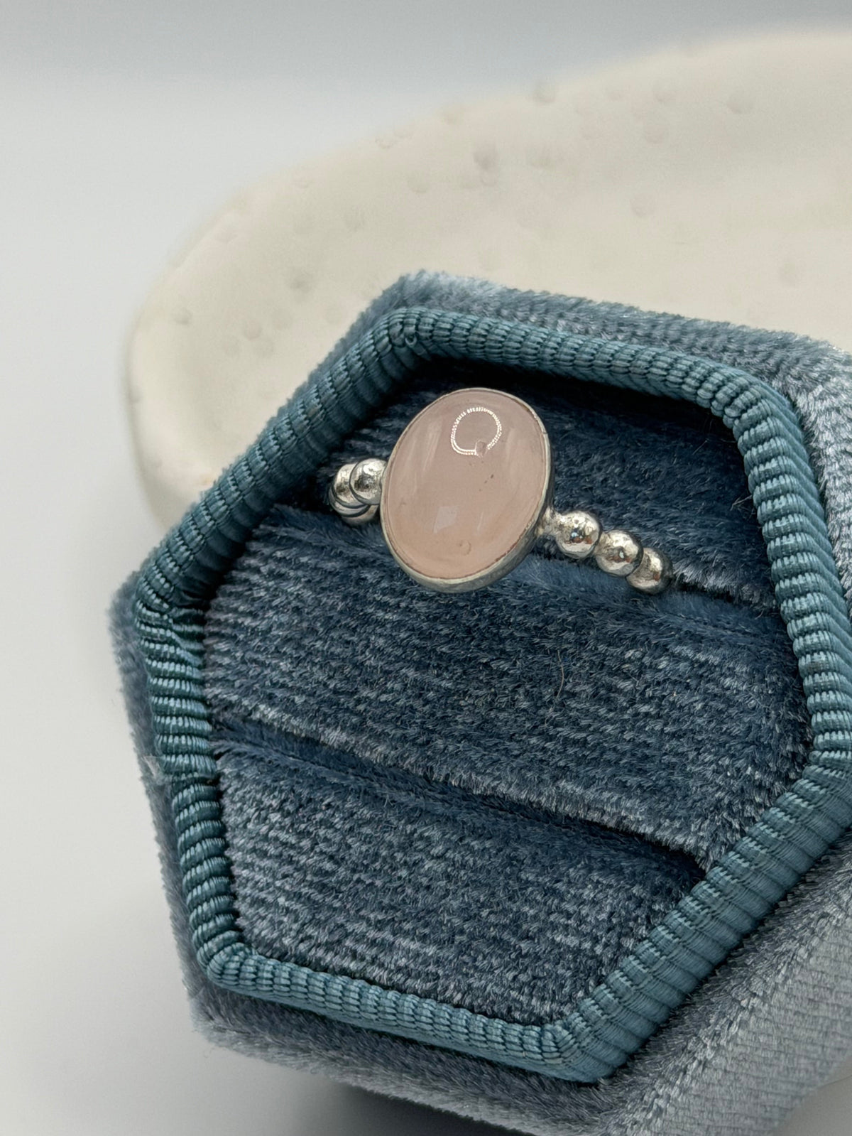 A One-of-a-kind rose quartz bobble ring from the Stone + Silver collection by Wild One Jewellery, featuring a pale pink oval cabochon set in a sterling silver band with decorative silver bobble details, displayed in a blue velvet ring box.